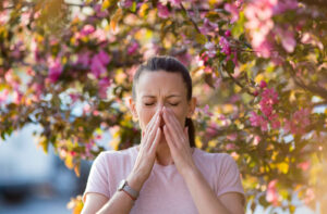 A woman sneezing due to allergies