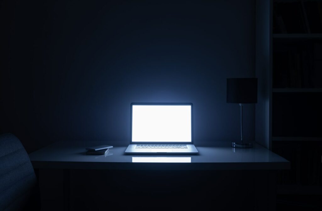 A dark room illuminated by a bright computer screen at night.