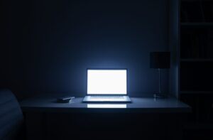 A dark room illuminated by a bright computer screen at night.