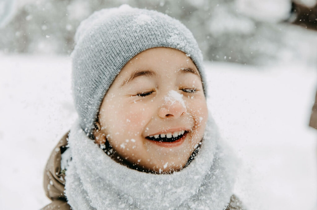 A young child enjoys playing in the snow.