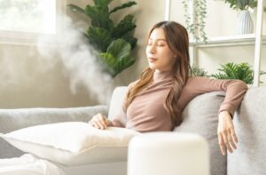 A person relaxes on their couch and enjoys the moist air created by their humidifier.