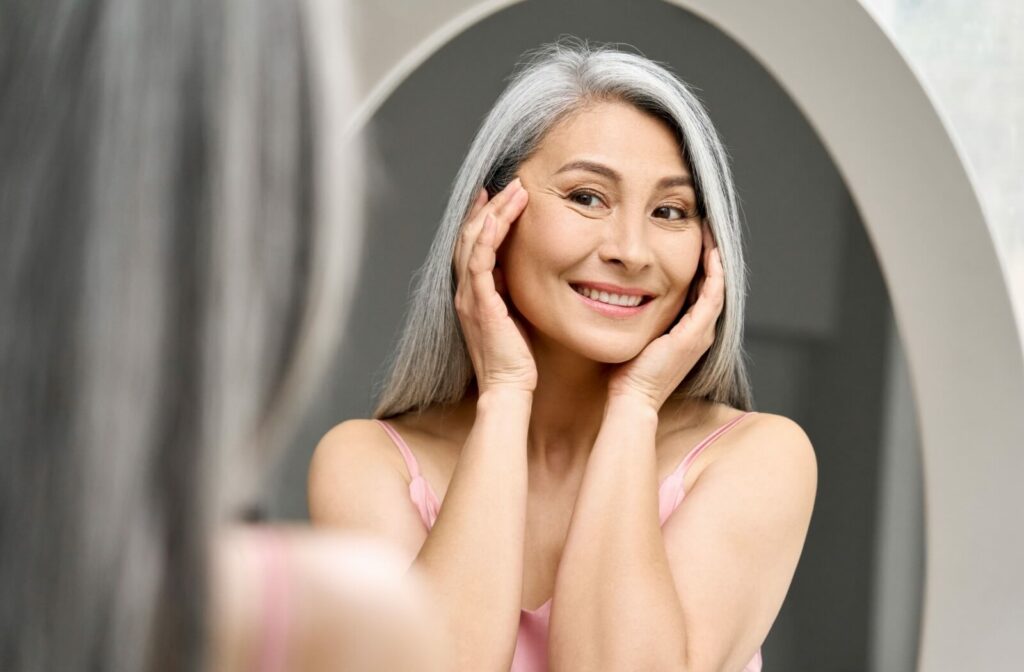A person with mature skin admires their reflection in the mirror.