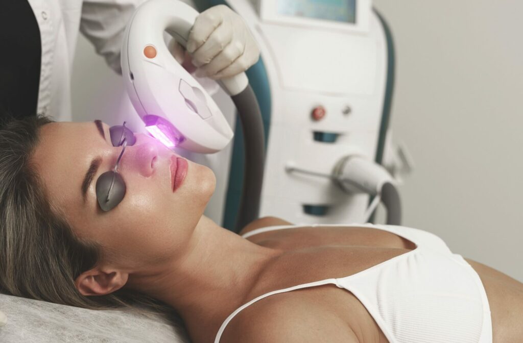 A patient lying on a table with eye coverings on while receiving IPL Therapy.