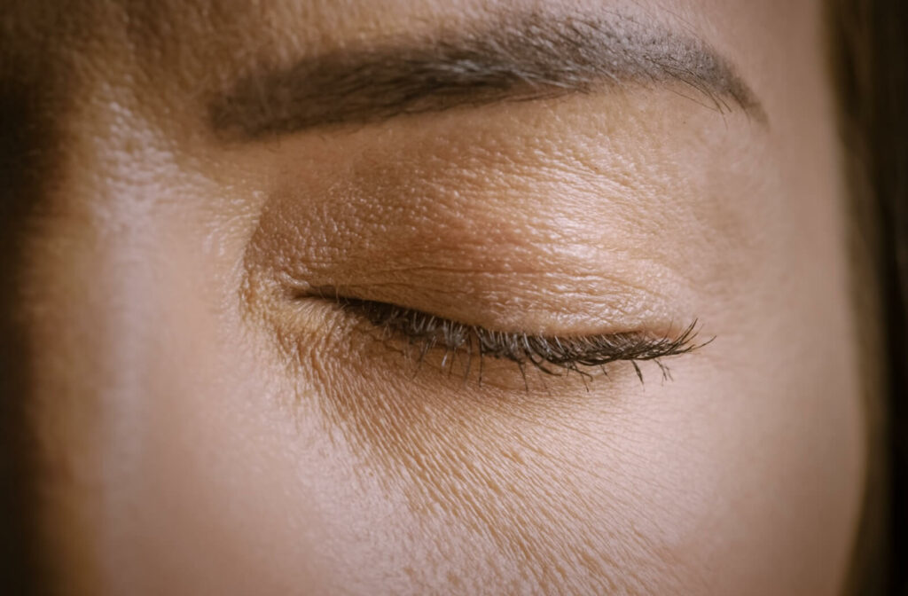 Close-up of an individual’s eye tightly closed as if experiencing pain or discomfort.